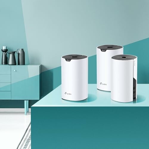 Three mesh routers on a table in a modern room